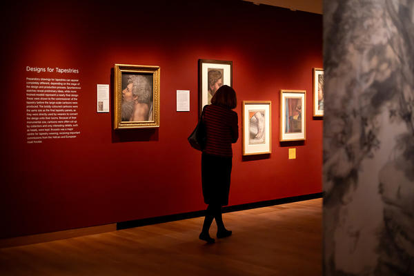 Inside the Bruegel exhibition preview looking at the tapestry artworks on a dark red wall