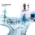 Radiohead's album cover artwork for OK Computer showing a blurry intersection of roads in abstract in greys and blues on a white background with a shadowy figure and an x on the right